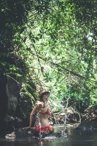 在丛林河里的年轻的旅行妇女。巴厘岛雨林。旅游探险概念