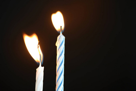 两支生日蜡烛在黑暗的背景下关闭照片