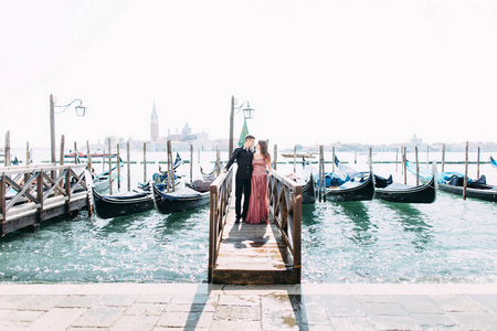 在威尼斯度蜜月期间，在贡多拉斯附近的木墩上摆着一对情侣