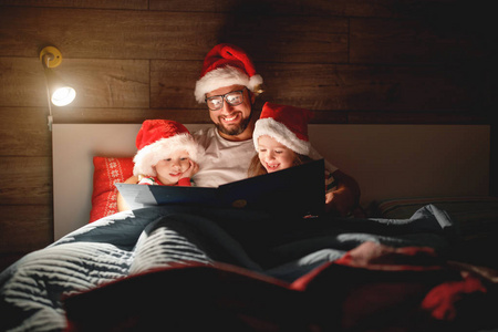 圣诞快乐 家父在睡觉前给孩子们读一本书