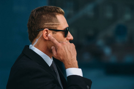 户外通讯男性保镖通过耳机户外安全通讯工具交谈.