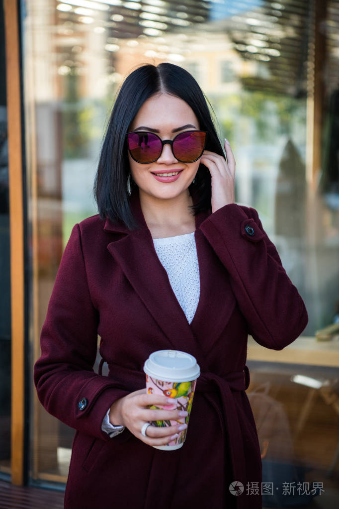 褐发女郎年轻的白人妇女在休闲夹克或大衣和太阳镜行走欧洲城市街道