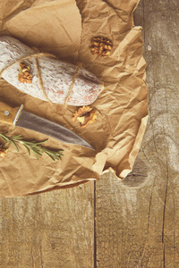 全意大利腊肠与迷迭香和刀在纸上。质朴的风格。顶部视图