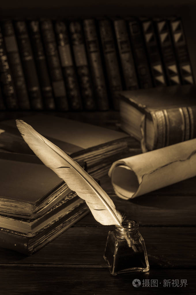 羽毛笔和一张卷起来的纸莎草纸放在一张木桌上上面有旧书的萼片效果