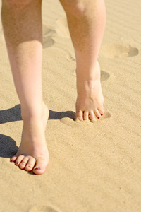 s feet close up on the clean beach sand, filmed from close up on