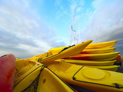 海岸上的一堆皮划艇靠在多云的蓝天上。 冒险旅行行动生活方式的概念。