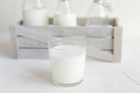 新鲜牛奶在瓶子和玻璃白色混凝土背景。 健康的食物厨房。