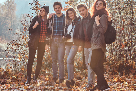 一群年轻的朋友拥抱在一起, lookina 在美丽的秋天森林相机