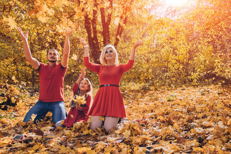 秋天美丽的年轻愉快的家庭投掷叶子