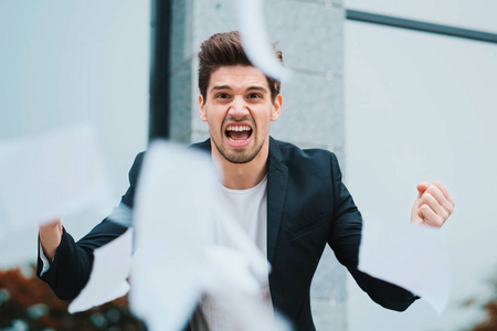 愤怒愤怒的男性办公室工作人员扔皱巴巴的纸，在工作中神经崩溃，在愤怒压力管理精神痛苦问题中尖叫，在失败时发脾气。