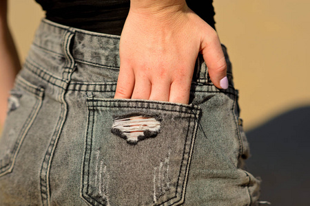 s hand with his wiped hole pocket jeans