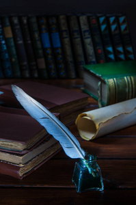 一支羽毛笔和一张卷起来的纸莎草纸放在一张木桌上，上面放着旧书