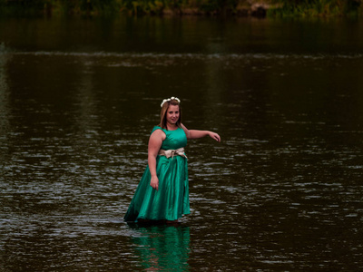 一位穿着绿色派对礼服的河中欢快的年轻女子的肖像