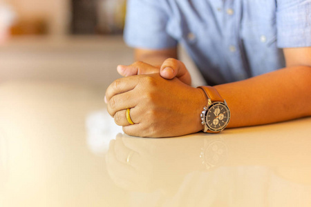 s left hand with gold wedding ring on his finger on marble table