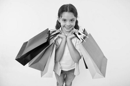 时尚专家。儿童可爱的购物专家帮助携带包裹在购物期间。小商店专家。女孩购物狂喜欢逛街。孩子女孩快乐的面孔运载束包裹黄色背景