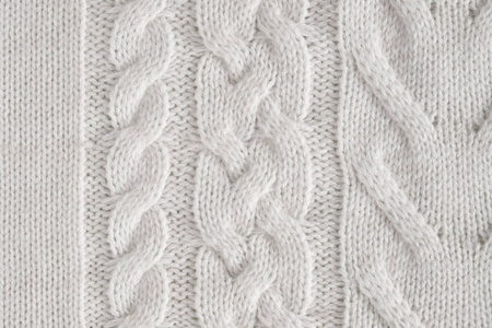 接近白色针织羊毛织物的纹理背景与图案顶部视图。