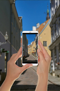 一位游客正在用手机拍摄爱沙尼亚塔林老城中心一条狭窄的街道。