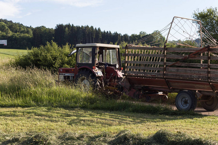 德国南部农村的一个阳光明媚的晚上，一位资深农民海伊在一个夏天的田野里和一位老拖拉机在一起