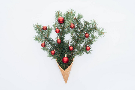 圣诞树上的红色圣诞玩具在松树枝上的顶部，在白色的冰淇淋锥上隔离