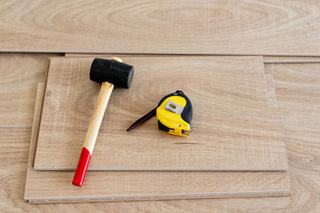 安装锤在室内安装层压实木复合地板.地板上躺着不同的木匠工具.