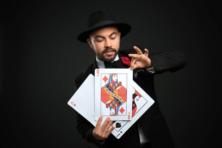 男性魔术师在黑暗背景下用纸牌表演魔术