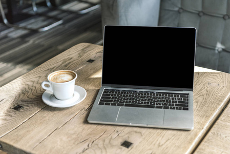 咖啡屋的乡村木桌上有空白屏幕的咖啡和笔记本电脑