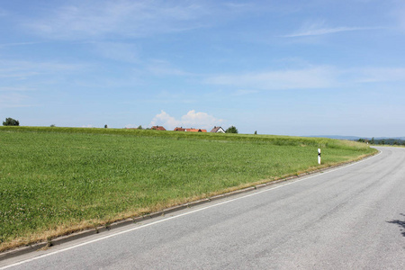 在六月的一个阳光明媚的日子里，在德国南部，你可以看到夏天的风景，有绿色和蓝色的天空，还有通往地平线的路标