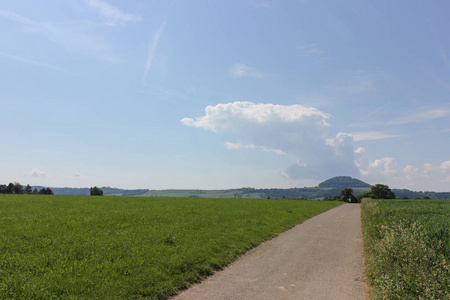 在六月的一个阳光明媚的日子里，在德国南部，你可以看到夏天的积云，在景观之上，把草坪的绿色与蓝天和阳光结合在一起