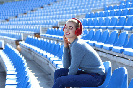 在体育场听音乐的漂亮年轻女子