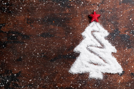 圣诞树形状的雪和红星装饰木制背景