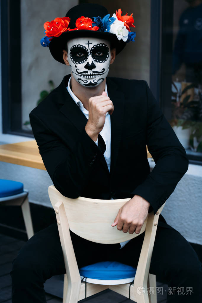 一个画着骷髅脸的人白天在城里死了一只僵尸. 万圣节鬼鬼祟祟戴着帽子