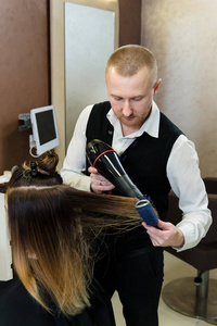 s hair. Making hairstyle using hair dryer