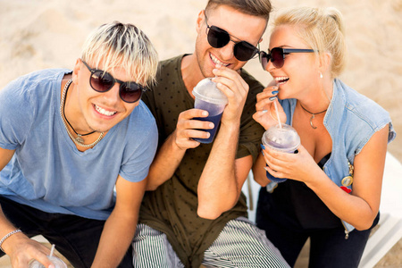 三个朋友在海滩上喝鸡尾酒，玩得很开心