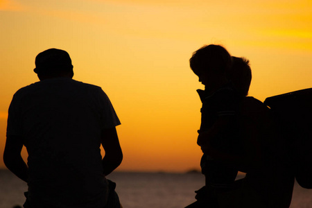日落时分，一家人带着孩子在海滩上的剪影