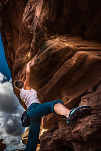 美国犹他州峡谷地一块美丽的红岩上的女子攀岩练习巨石