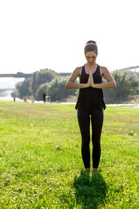 年轻的运动女性练习哈他瑜伽姿势，穿着紧身裤和辫子。
