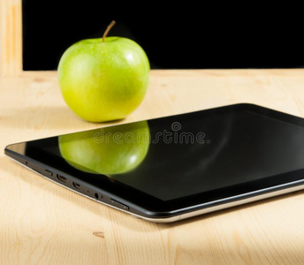 木桌黑板前的数字平板电脑和青苹果