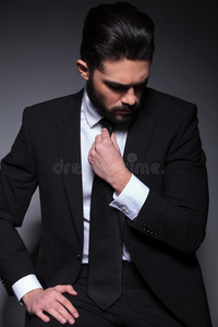 年轻的时尚男士低头修好领带图片