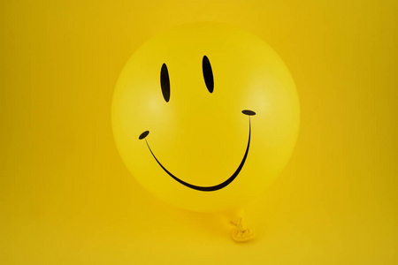 快乐表情气球股票图像。 黄色气球股票图像。 微笑充气气球孤立在黄色背景上。 笑话晚会