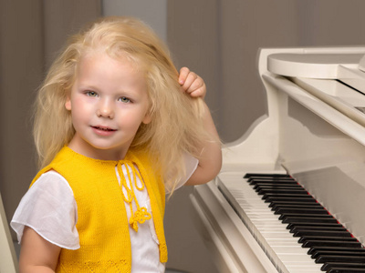 漂亮的小女孩正在玩一架白色的大钢琴