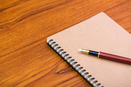 钢笔或墨水笔与笔记本纸在木制工作桌上与复印空间办公桌的概念理念。
