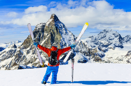 人在新鲜的粉末雪上滑雪。 滑雪在冬季季节，山和滑雪巡回越野设备在雪山顶部在阳光明媚的一天与马特霍恩在背景泽马特在瑞士阿尔卑斯山。