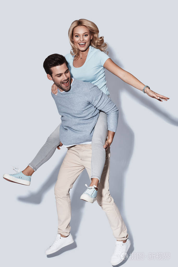 顽皮英俊的年轻男子背着女人背着背骑