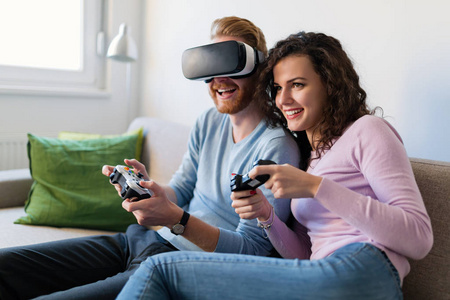 快乐的年轻夫妇在家玩虚拟现实耳机的电子游戏