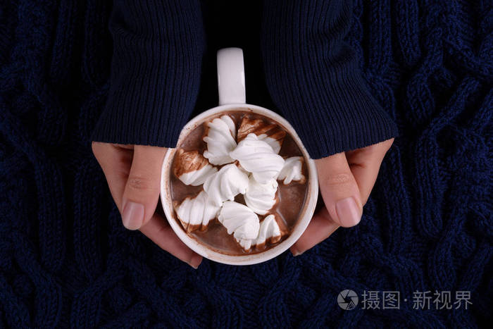女人的手拿着热巧克力和棉花糖糖在蓝色针织格子上面的风景复制空间