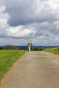 在一个阳光明媚的日子里，9月底，在斯图加特市附近的乡村景色中，与一位年长的男士在绿色田野和蓝天摇床旁散步