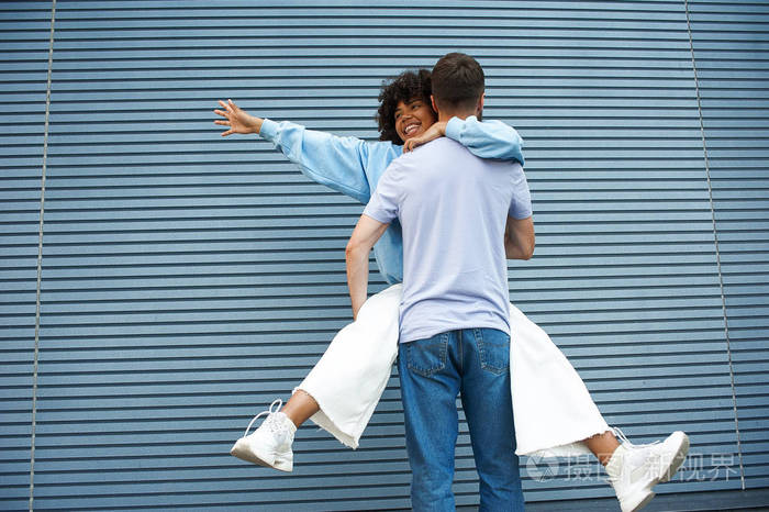 快乐的年轻夫妇拥抱微笑的穆拉托女孩挂在她的bf,她的手指向左,并展开