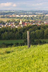 草地围栏，村庄背景在绿色草地和9月秋季德国南部