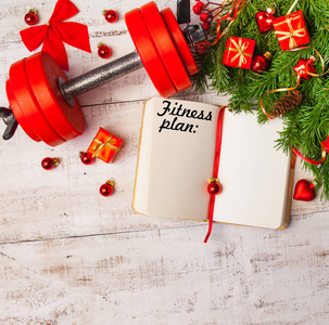圣诞节背景与日记哑铃红色礼品盒杉树枝在白色木材背景复制空间。 平躺顶部视图。 规划概念