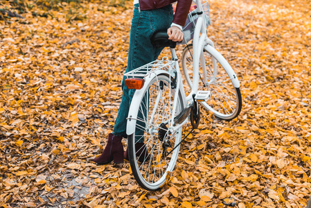 秋色森林中骑自行车的时尚女性形象